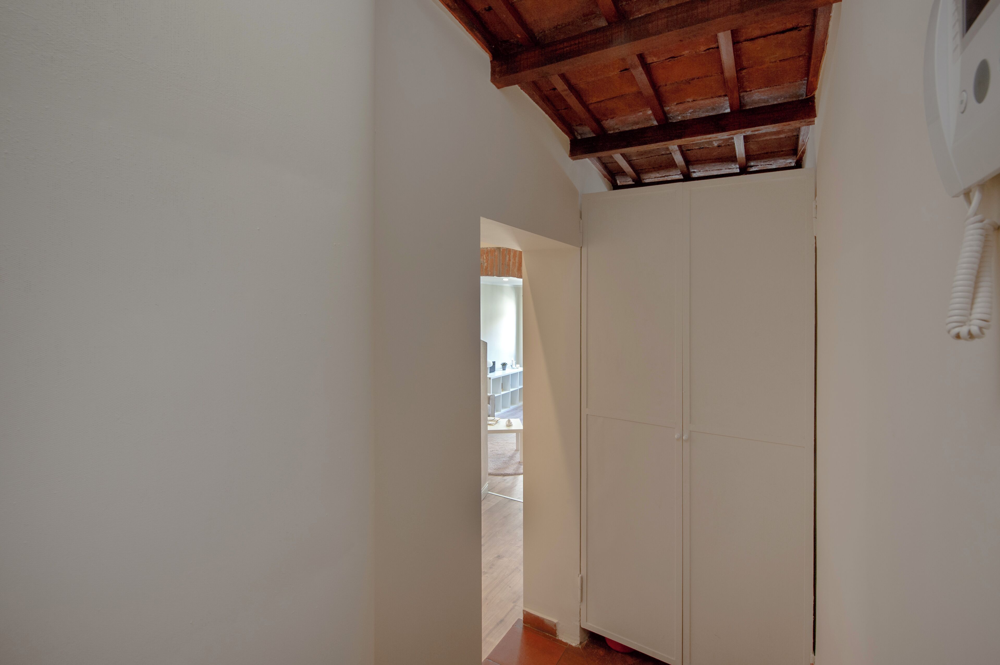A hallway with a wooden ceiling and a white door.