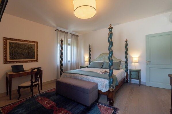 Une chambre à coucher avec un lit à baldaquin, un bureau avec un ordinateur portable, une chaise et un tapis.