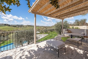 Zona de estar al aire libre con techo y vistas a una piscina y al campo.