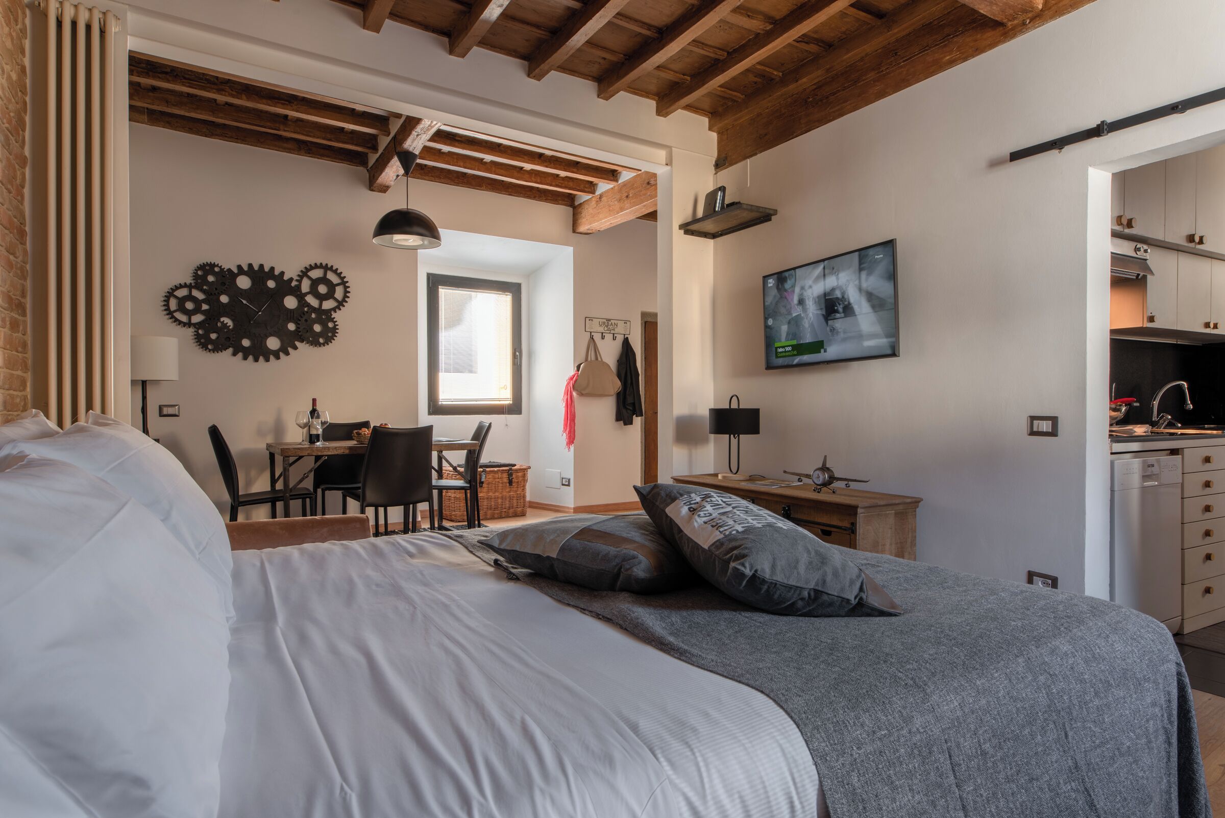 A bedroom with a large bed, a desk, and a television in the corner.