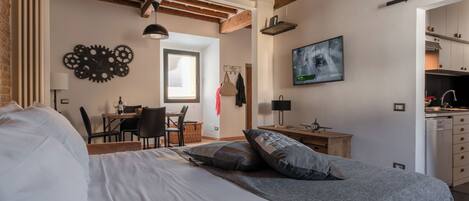 A bedroom with a large bed, a desk, and a television in the corner.