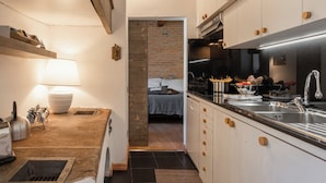 A compact kitchen with a built-in stove, a sink, and wooden cabinets. - Santa Trinita - Flo Apartments (Florence)