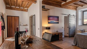 A cozy room with a wooden dining table, a bed, and a TV mounted on the wall. - Santa Trinita - Flo Apartments (Florence)