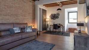 A cozy living room with a leather sofa, a dining area with a table and chairs, a brick wall, and a wooden ceiling. - Santa Trinita - Flo Apartments (Florence)