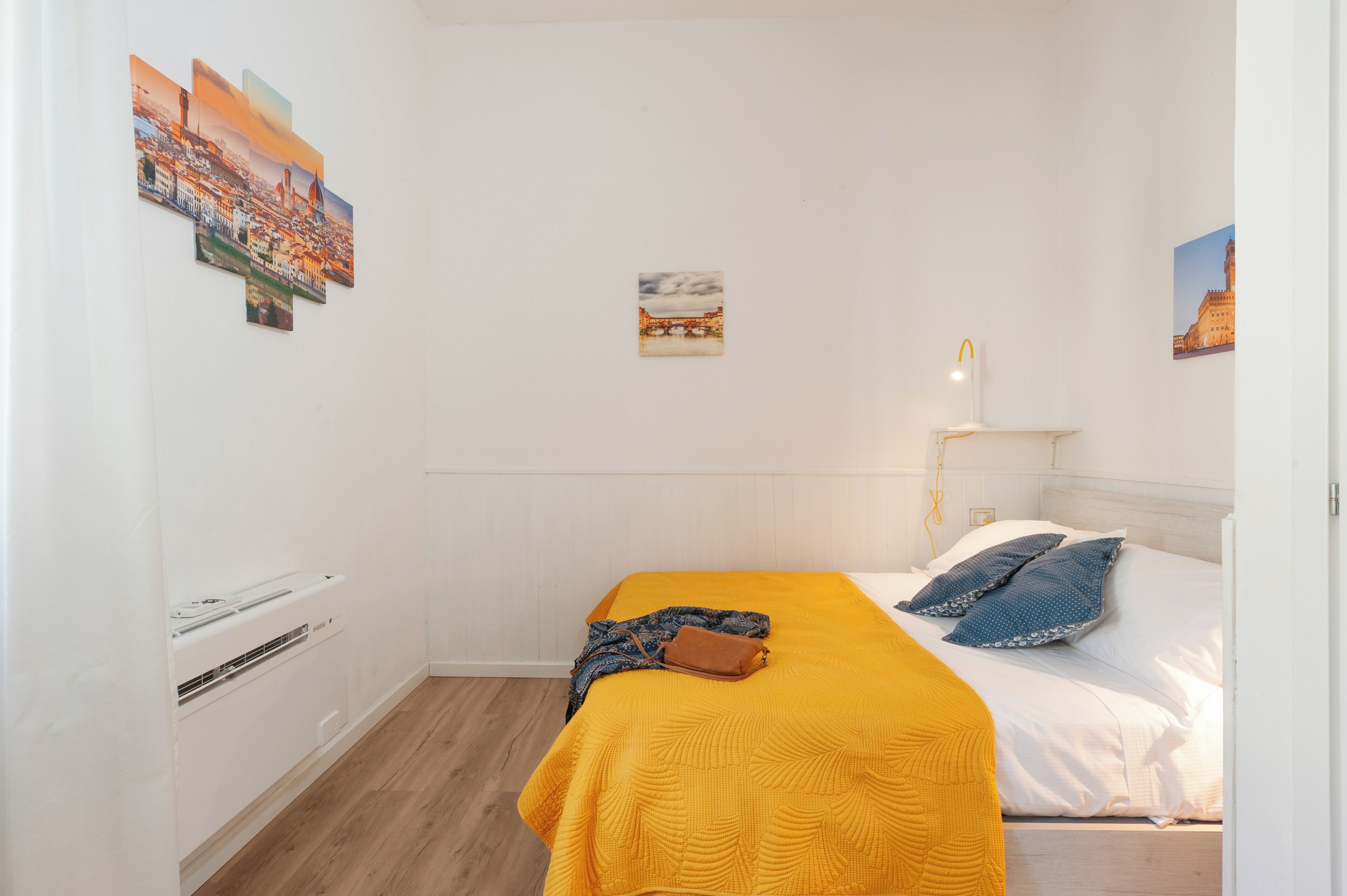 Een hotelkamer met een bed, een nachtkastje met een lamp en decoratie aan de muur.