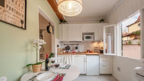 Una cucina compatta con mobili bianchi, un forno a microonde e un'area pranzo con tavolo apparecchiato per due.