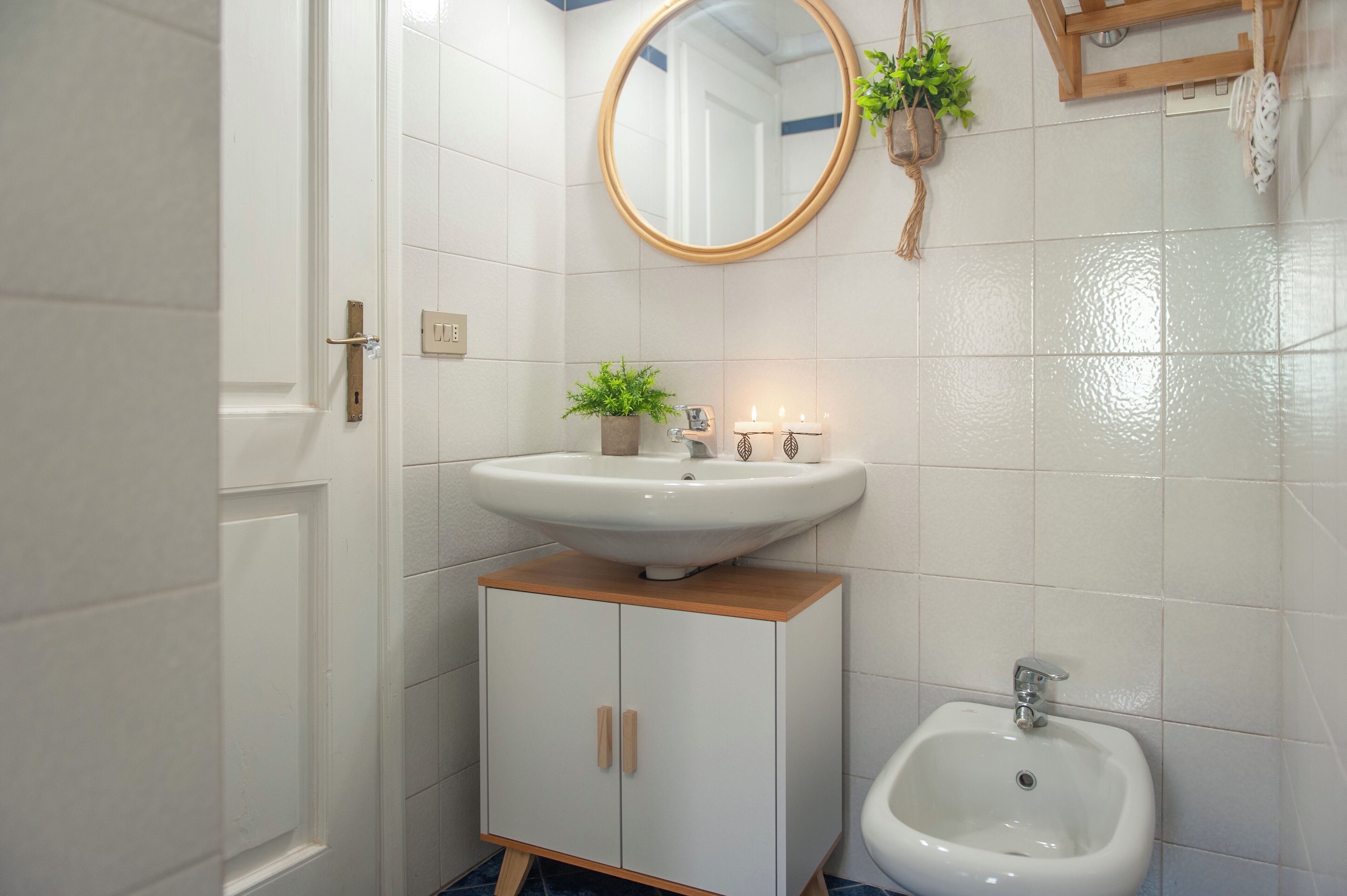 Ein Badezimmer mit einem weißen Waschbecken, einem Spiegel, einem Schrank und einem Bidet.