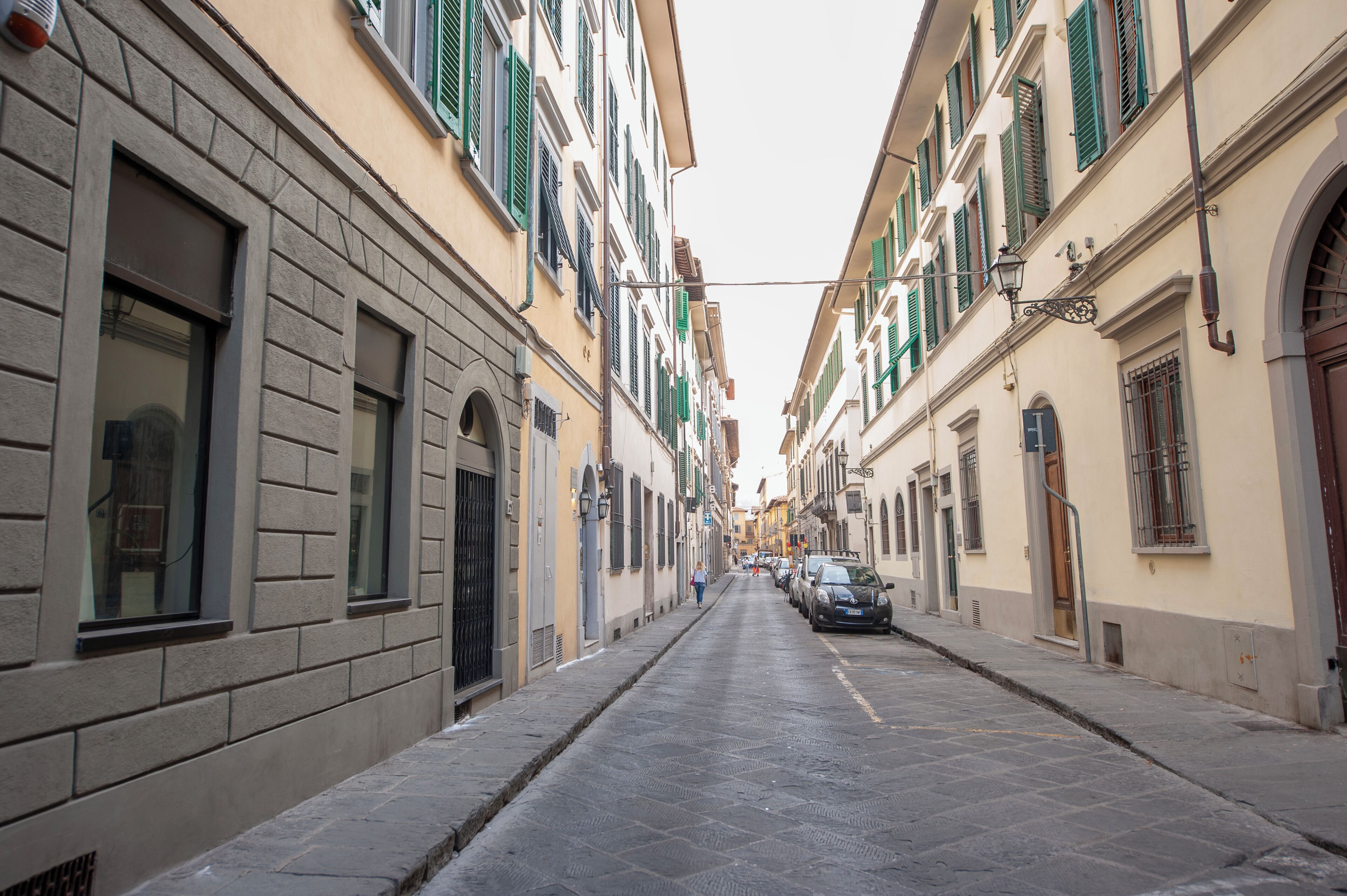 A narrow street lined with buildings featuring large windows and shutters.