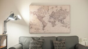 A grey sofa with patterned cushions, a world map on the wall, and a desk lamp. - Canto Rivolto - Flo Apartments (Florence)