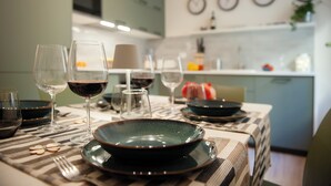 A dining table set with plates, glasses, and cutlery in a modern kitchen with a clock on the wall. - Canto Rivolto - Flo Apartments (Florence)