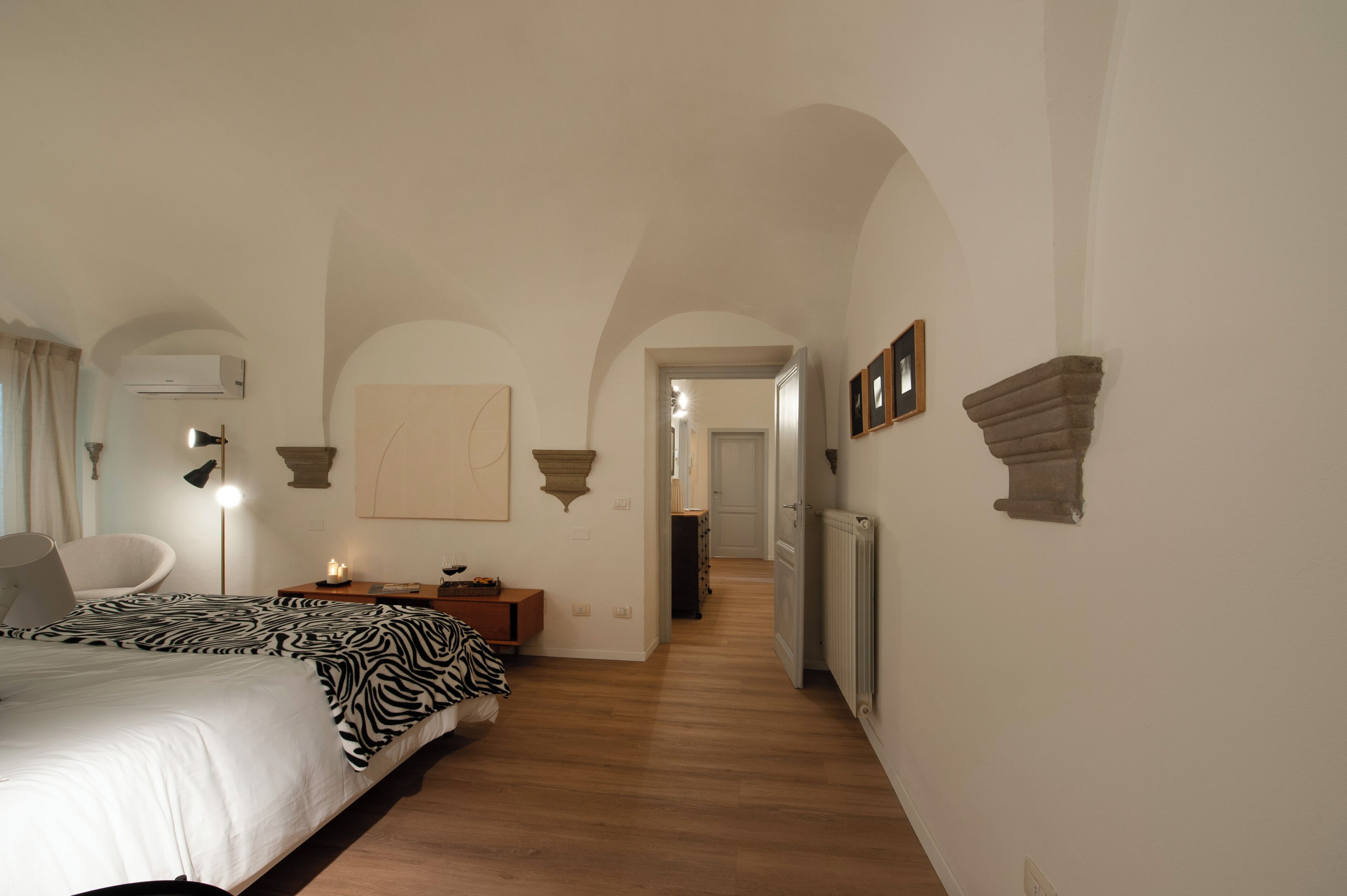 A bedroom with a bed, bedside lamp, and a zebra-patterned throw.