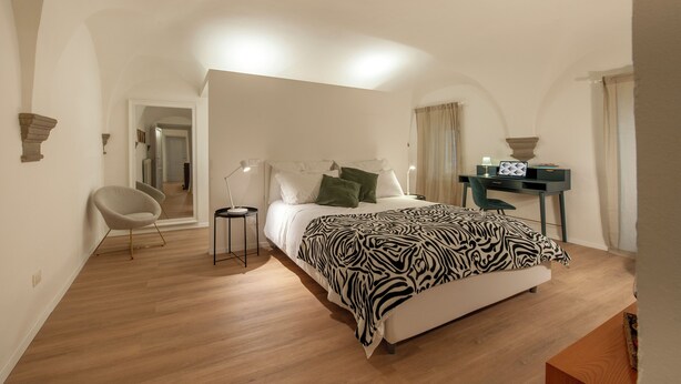 A bedroom with a bed, a desk, a chair, and a mirror. - Canto Rivolto - Flo Apartments (Florence)