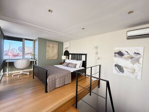 A modern bedroom with a bed, desk, chair, and artwork. - Spacious Duplex Haven | Bosphorus View & Elevator (Istanbul)