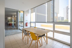 A spacious room with a large window, a wooden table with chairs, and a fire extinguisher on the wall. - Studio 'Casa Onze' with Sea View, Wi-Fi and Air Conditioning (Portimão)