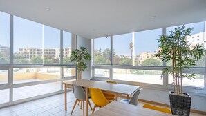 Moderni ruokailutila, jossa on suuret ikkunat, puinen pöytä ja kaksi tuolia.