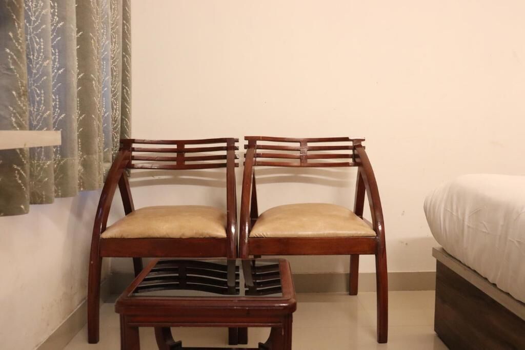 Une pièce comprenant deux chaises en bois, dotées d’assises rembourrées, et une petite table en bois.