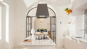 Una cocina moderna con una isla, muebles blancos y un arco negro.