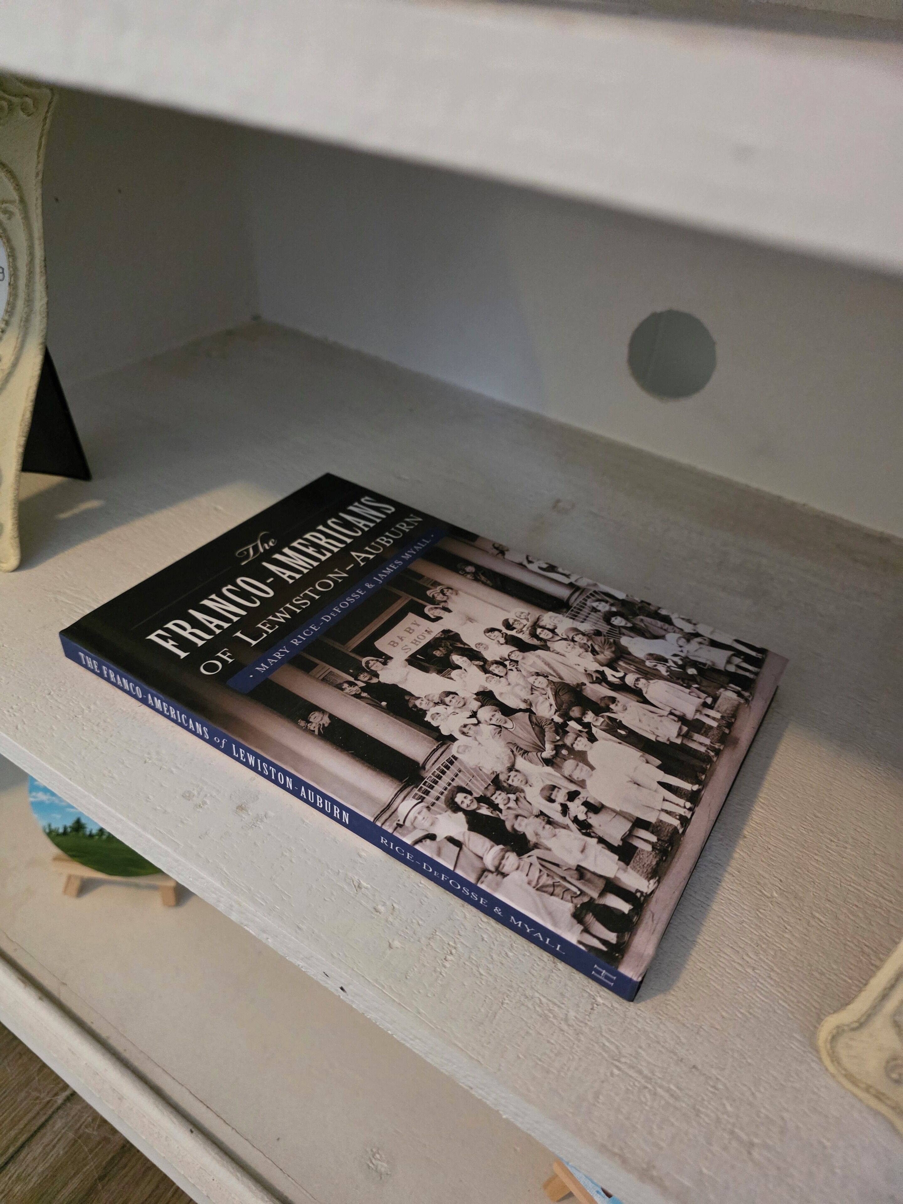 A book titled 'The Franco-Americans of Lewiston-Auburn' on a shelf.
