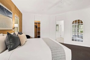 A bedroom with a bed, a closet, a window, and a painting on the wall.