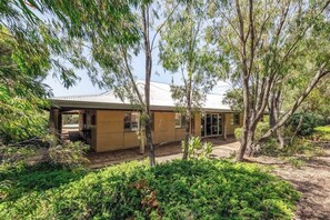 A house with a covered outdoor area, surrounded by dense greenery and trees. - Waterlily Retreat—Bushland Serenity near the Beach (Eagle Bay)