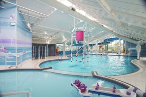 En indendørs swimmingpool med rutsjebane, en redningsplatform og et bassinområde med siddepladser.