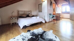 Quarto com teto de madeira, cama, cadeira, cômoda e tapete de couro de vaca.