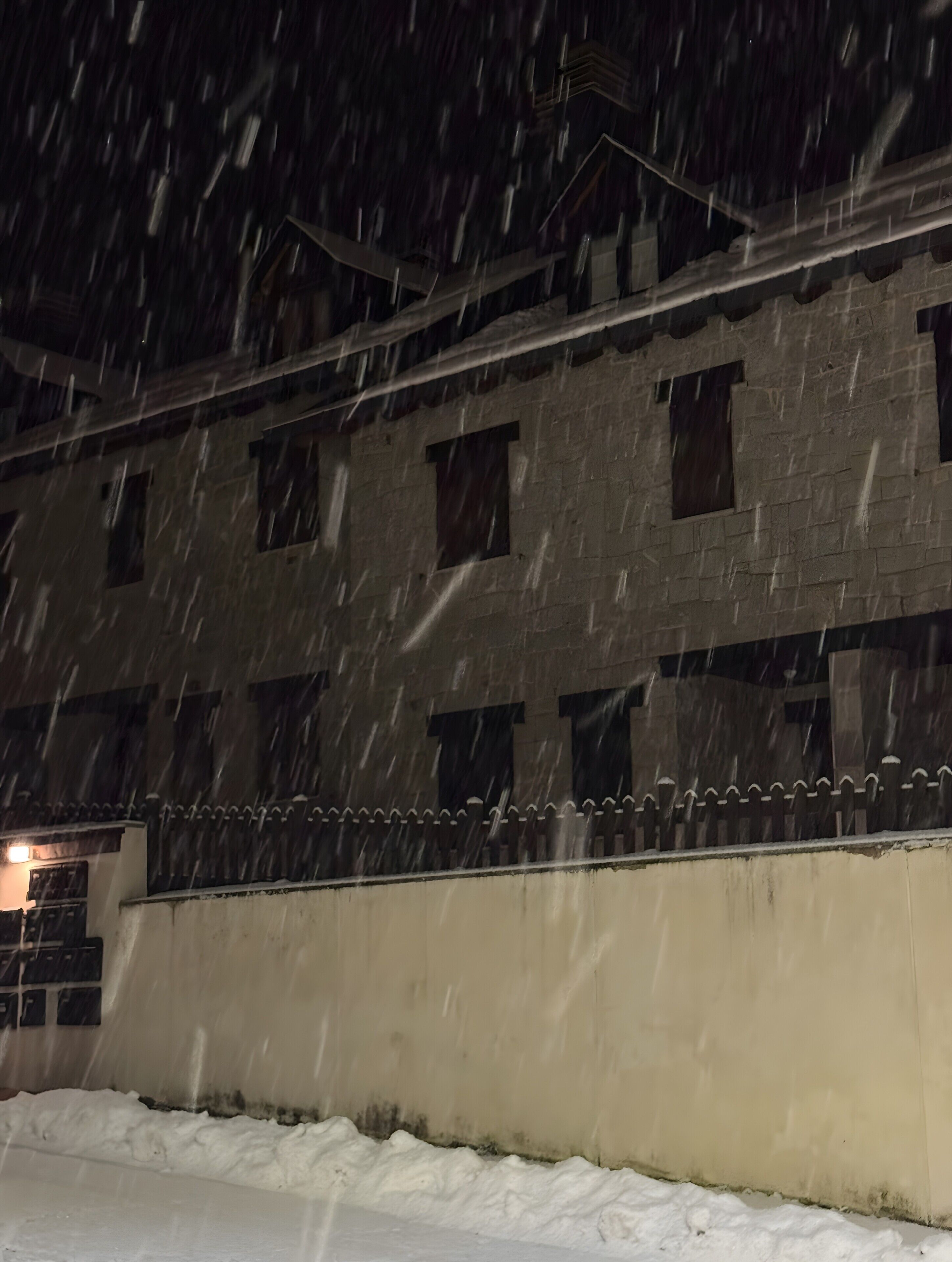 Um edifício com várias janelas e o chão coberto de neve.