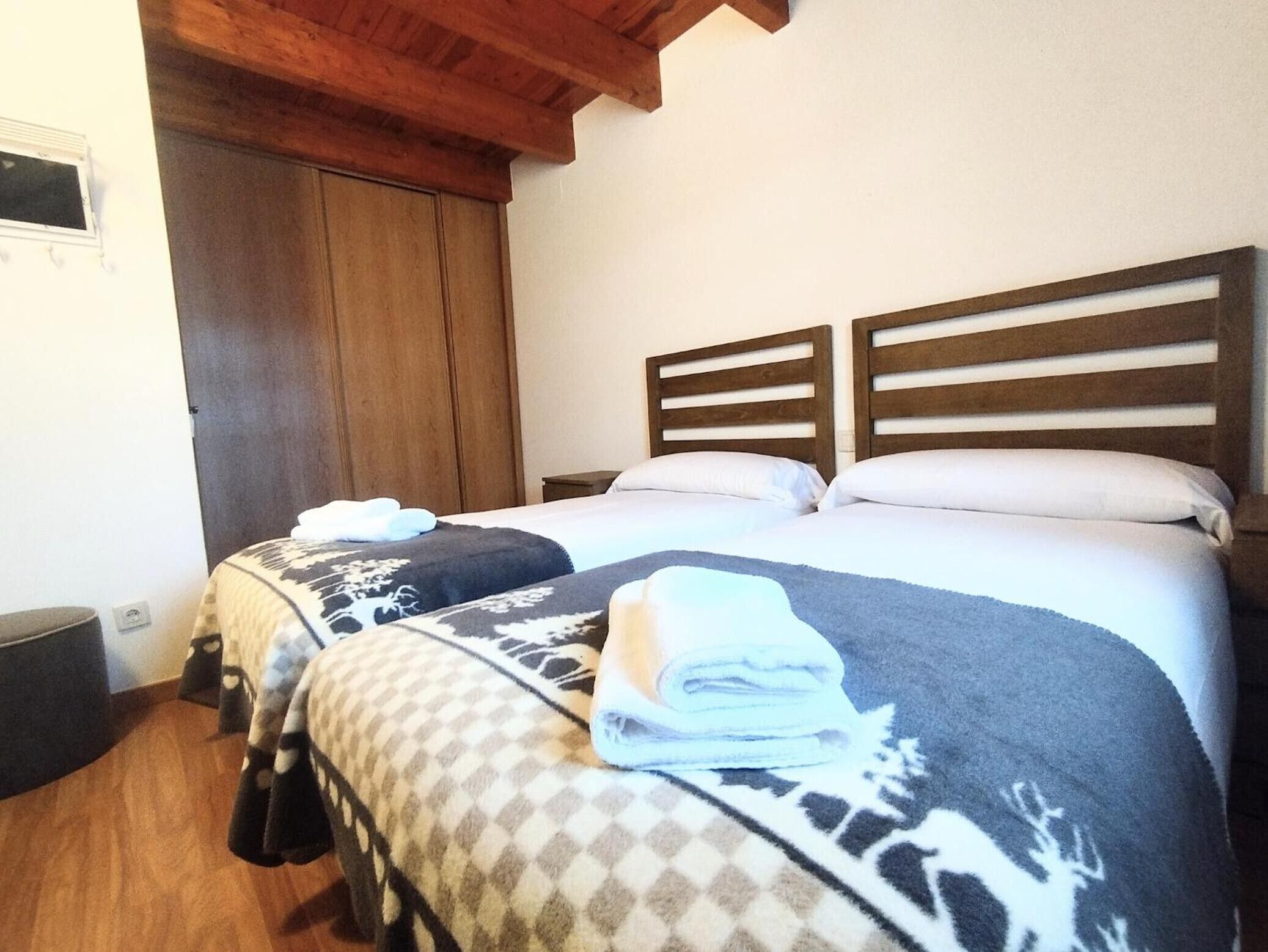 Een hotelkamer met twee bedden, houten hoofdeinden, een groot raam en een houten plafond.