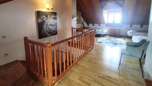 Um amplo loft com escada de madeira, um quadro na parede, uma janela com luz natural e um espaço de estar aconchegante.