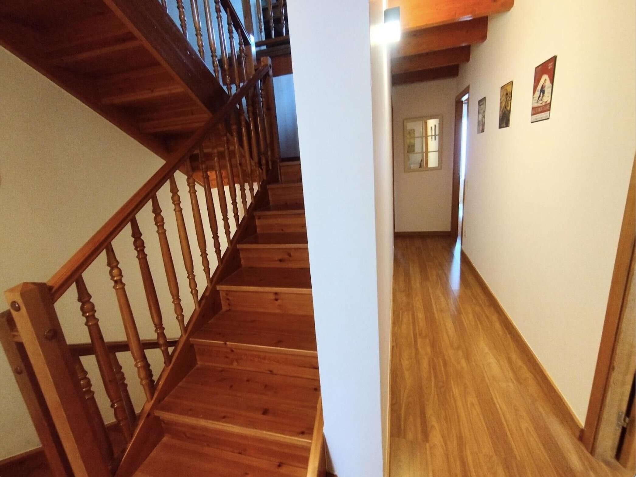 A wooden staircase leading to a hallway with wooden flooring and a door at the end.
