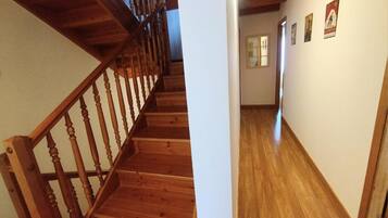 A wooden staircase leading to a hallway with wooden flooring and a door at the end.