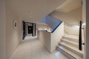 Eine moderne Hotelhalle mit einer Rezeption, einer Treppe und einer Tür zu einem weiteren Raum.