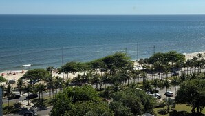 Une plage bordée de palmiers, avec une route au premier plan.