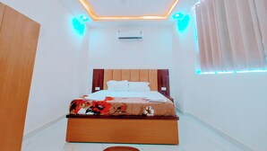 Une chambre à coucher comprenant un lit, un ventilateur de plafond, un appareil de climatisation et une fenêtre avec des stores.