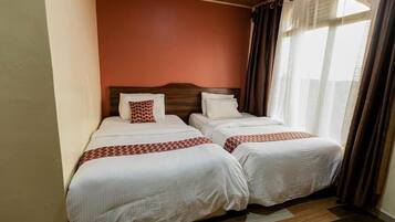 A hotel room with two beds, a wooden ceiling, and a view through sheer curtains.