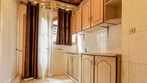 Un corridoio stretto con pavimento piastrellato, mobili in legno e una finestra con tende.