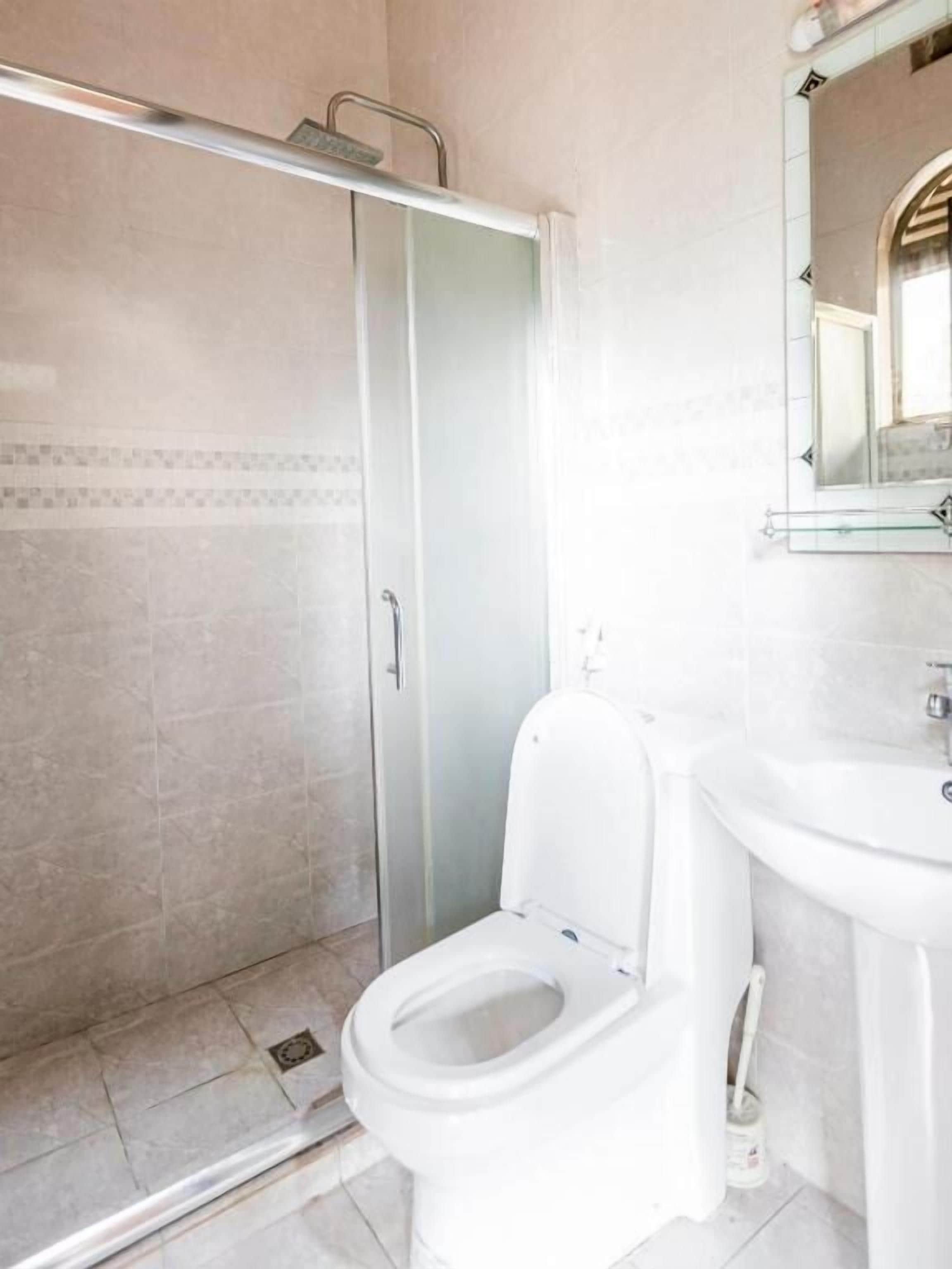 A bathroom with a glass shower enclosure, a white toilet, and a sink with a mirror above it.