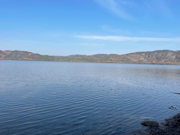 Un lago tranquilo con cielo despejado y colinas al fondo.