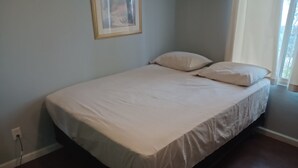 Un dormitorio con cama, enchufe y ventana con cortinas.