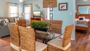 A living room with wicker furniture, a glass table, and a ceiling fan. - Rookery III 4009 | 3BR Cottage | 1/2 Mile to Beach | Screened-In Porch (Fort Morgan)
