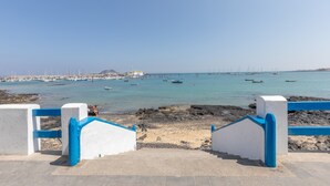 A coastal view with a clear sky, a sandy beach, and boats in the water. - Vacation Villa 'Atlantic Ocean Private Pool' with Sea View and Wi-Fi (Corralejo)