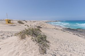 Une plage avec un poste de surveillance pour les sauveteurs, des dunes de sable et l’océan.