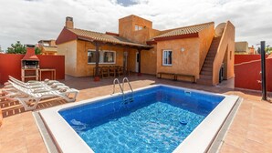 A swimming pool with a tiled deck, a barbecue grill, and a covered patio area. - Vacation Villa 'Atlantic Ocean Private Pool' with Sea View and Wi-Fi (Corralejo)