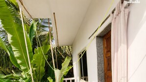 Un balcon avec une table et des chaises, une porte en bois et une vue sur une végétation luxuriante.