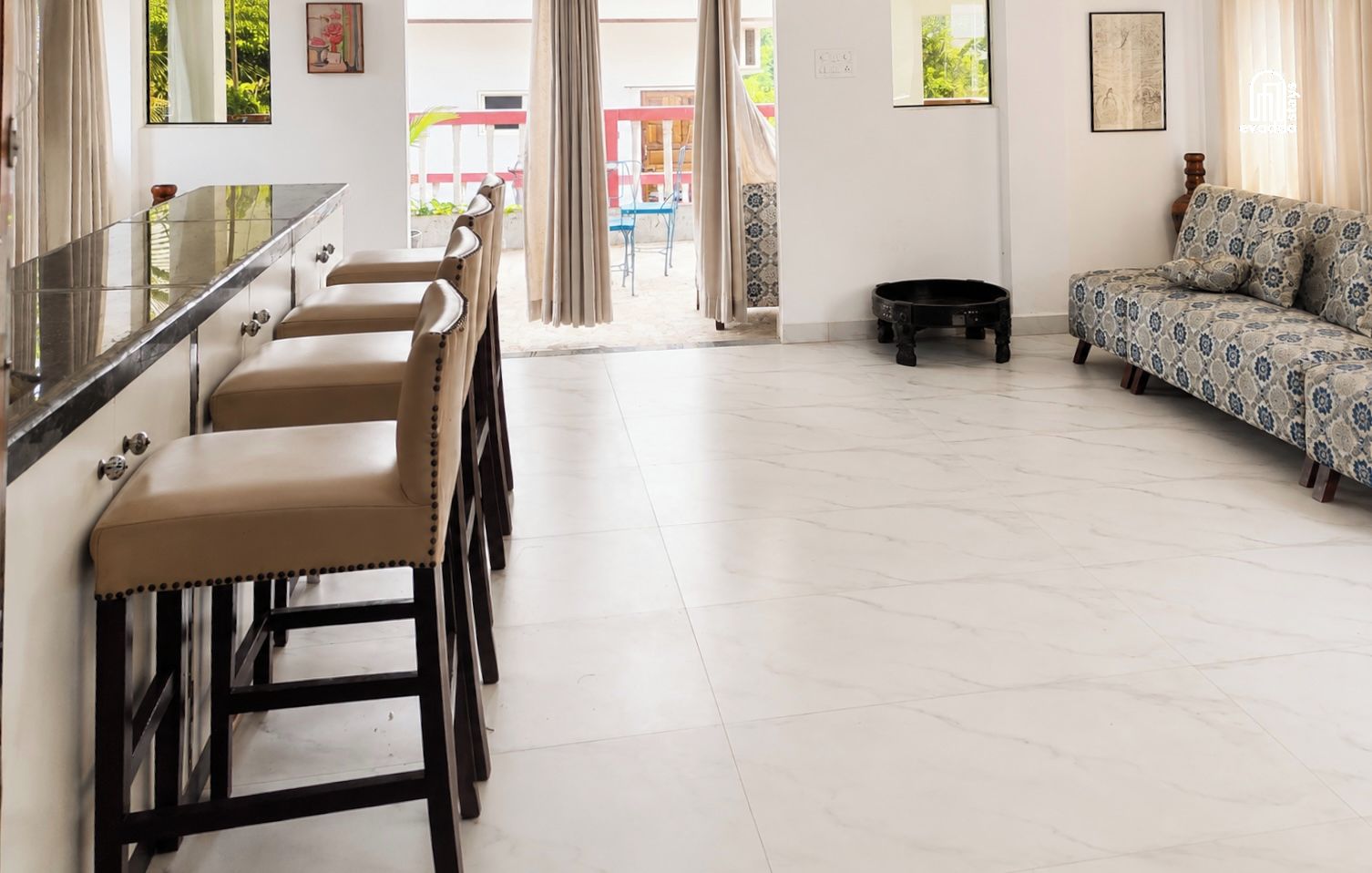 A spacious living area with a sofa, a dining table with chairs, and a kitchen counter.