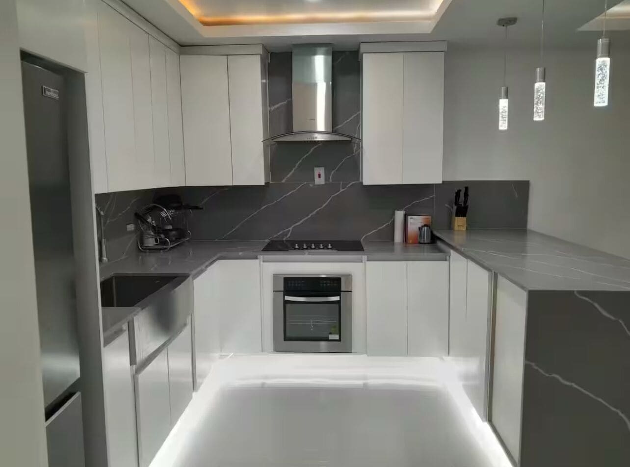 Cozinha moderna com armários brancos, forno embutido e bancada elegante.
