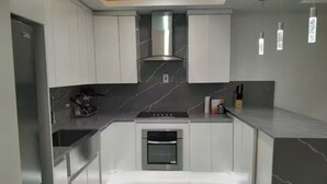 Eine moderne Küche mit weißen Schränken, einem eingebauten Ofen und einer eleganten Arbeitsplatte.