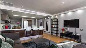 A modern living room with a sofa, a coffee table, a TV, and a kitchen area with bar stools. - Art Apartment 1304 in Cape Town (Cape Town)