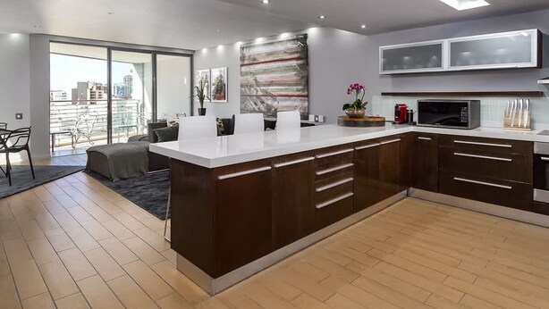 A modern kitchen with a central island, dark cabinetry, and a large window overlooking a cityscape. - Art Apartment 1304 in Cape Town (Cape Town)