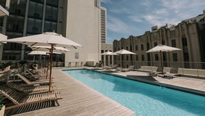 A pool area with lounge chairs and umbrellas, surrounded by modern buildings. - Art Apartment 1304 in Cape Town (Cape Town)